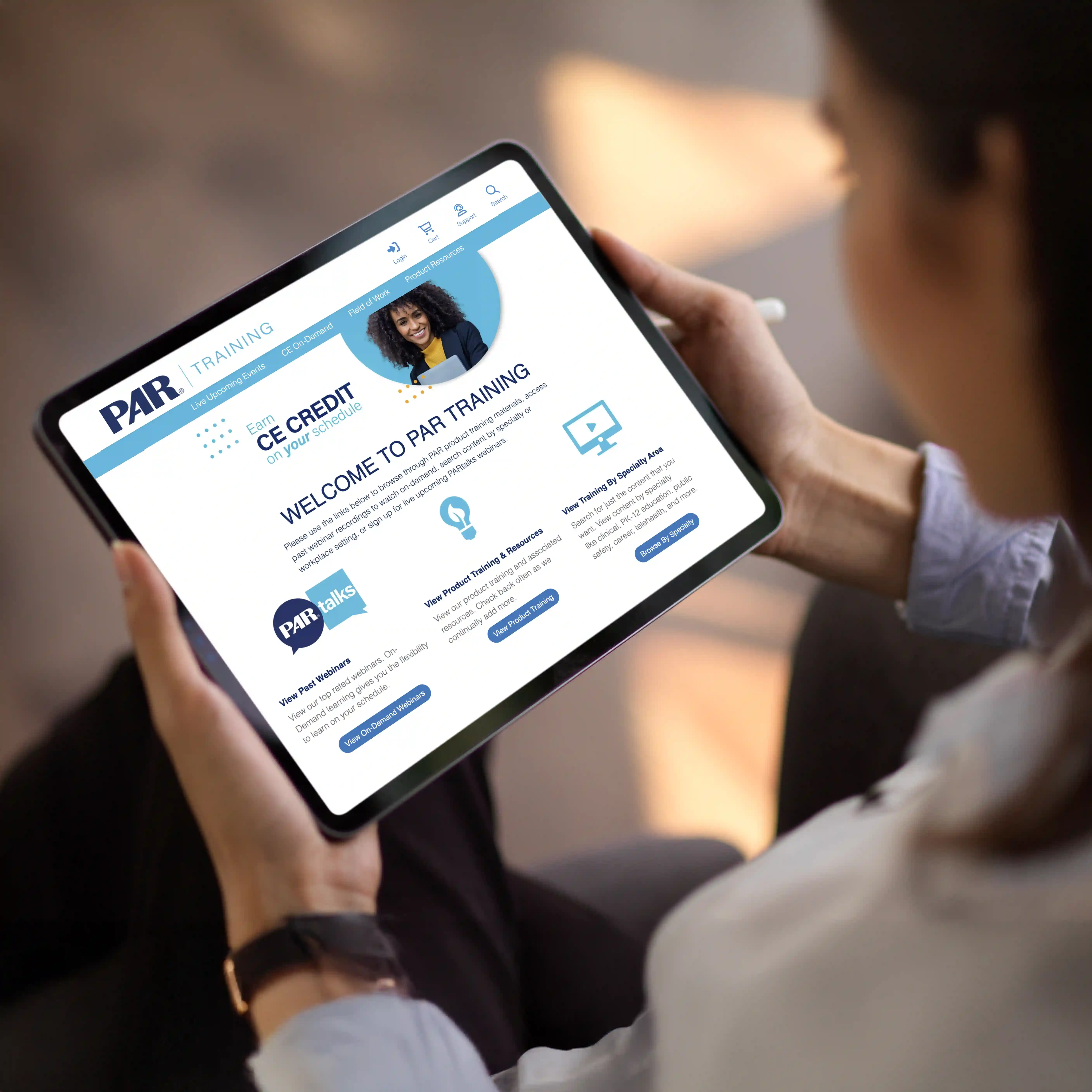 Woman is holding a tablet displaying the homepage of PARtraining platform