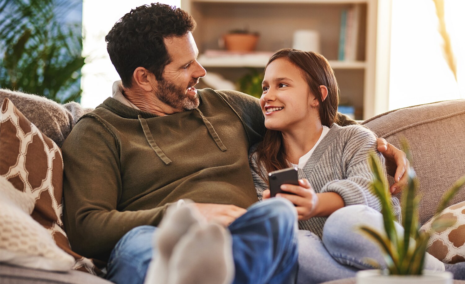 A father and daughter sitting next to each other on a sofa.