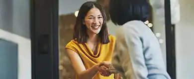 two professional women shake hands in an office