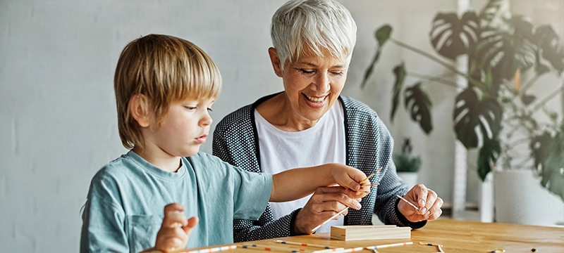 A young blonde boy plays an interesting game with his grandmother, representing executive functioning across the lifespan